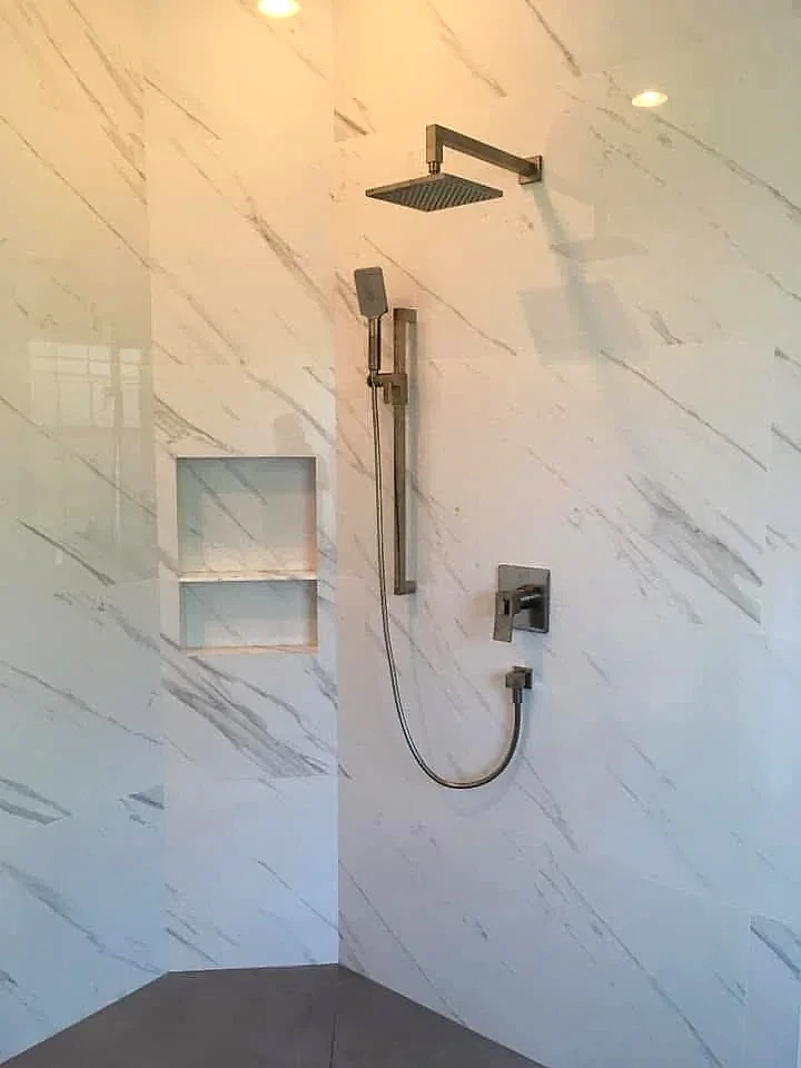 Shower head, handheld and valve trim installed on marble tile, South Florida